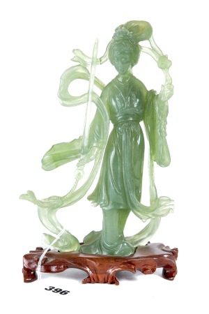 A CHINESE TRANSLUCENT GREEN HARDSTONE FIGURE OF GUANYIN holding a sword and flower,