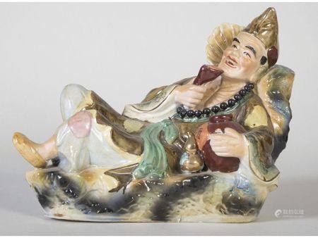 GLAZED AND GLAZED CERAMIC FIGURE, REPRESENTING A RECLINING DEITY DRINKING. 30 x 20 x 35 cm.